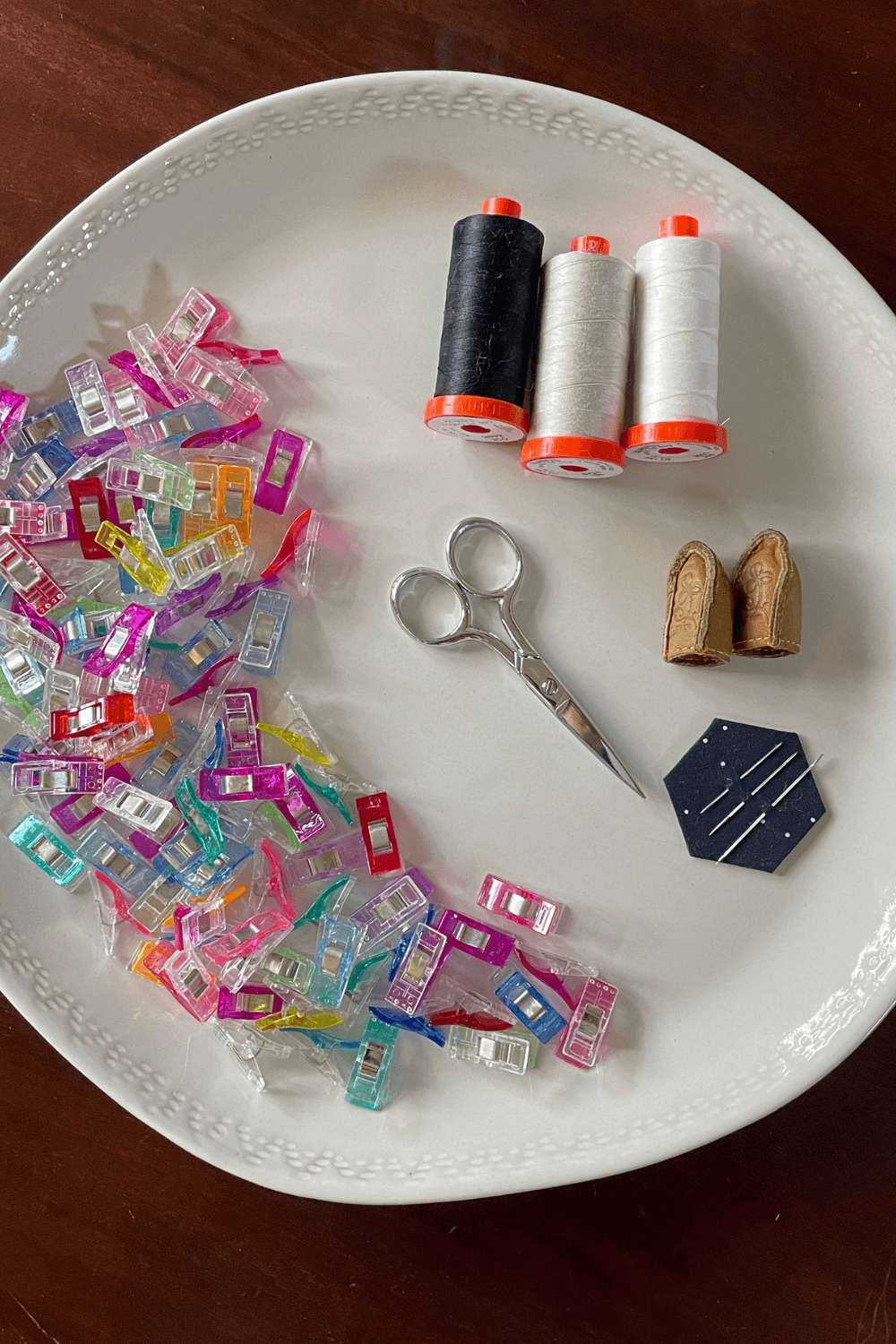 The contents of Cheryl's sewing kit displayed on a plate featuring her favourite notions and go-to leather thimble. See more over on Shannon Fraser Designs' blog #whatsinyoursewingbag #notions #quilting